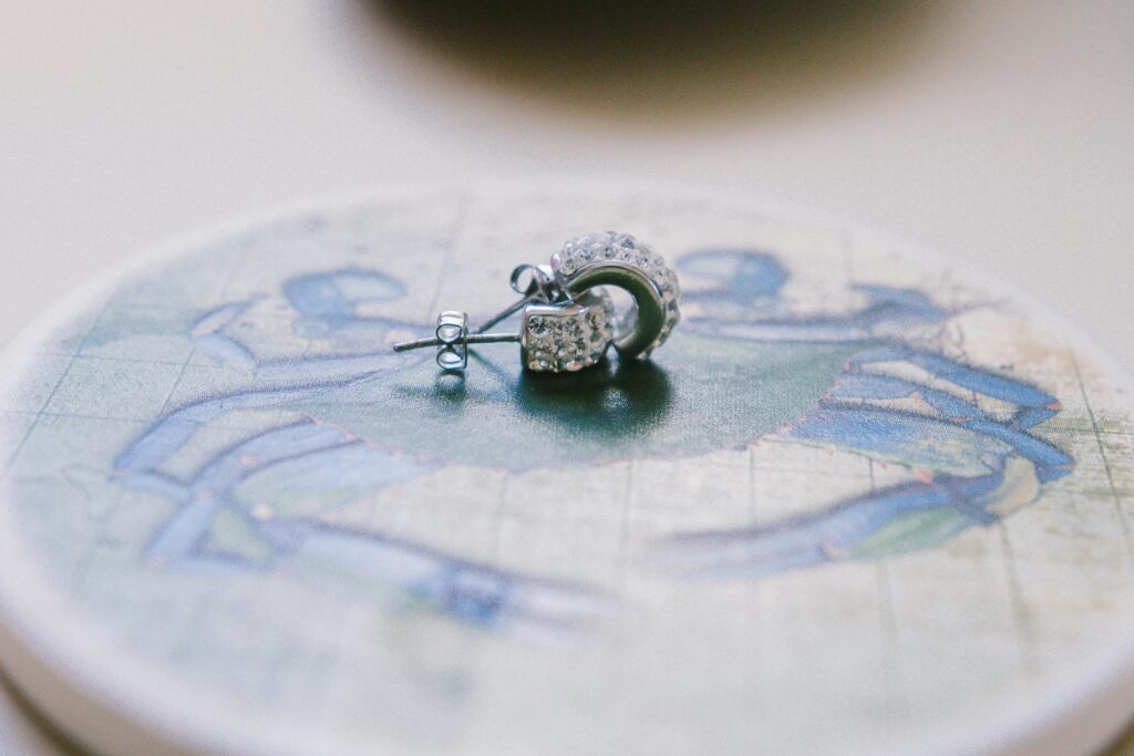 Close-up view of a pair of elegant silver earrings adorned with small diamonds, placed on a decorative surface.